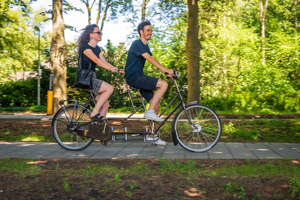 Woman and man cycling on tandem through Weert municipality