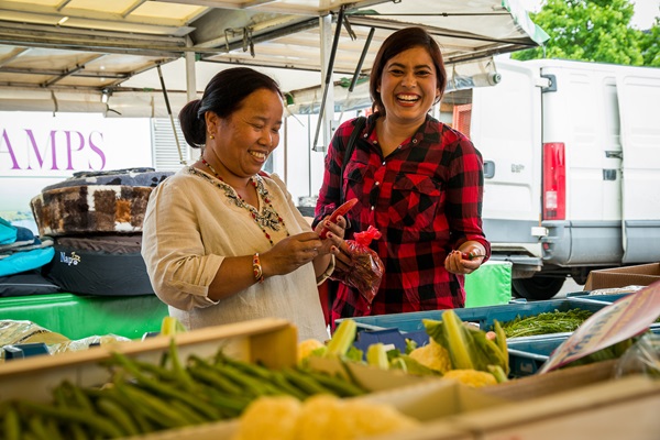 Vrouwen lachen terwijl ze inkopen doen bij de groentekraam op de markt