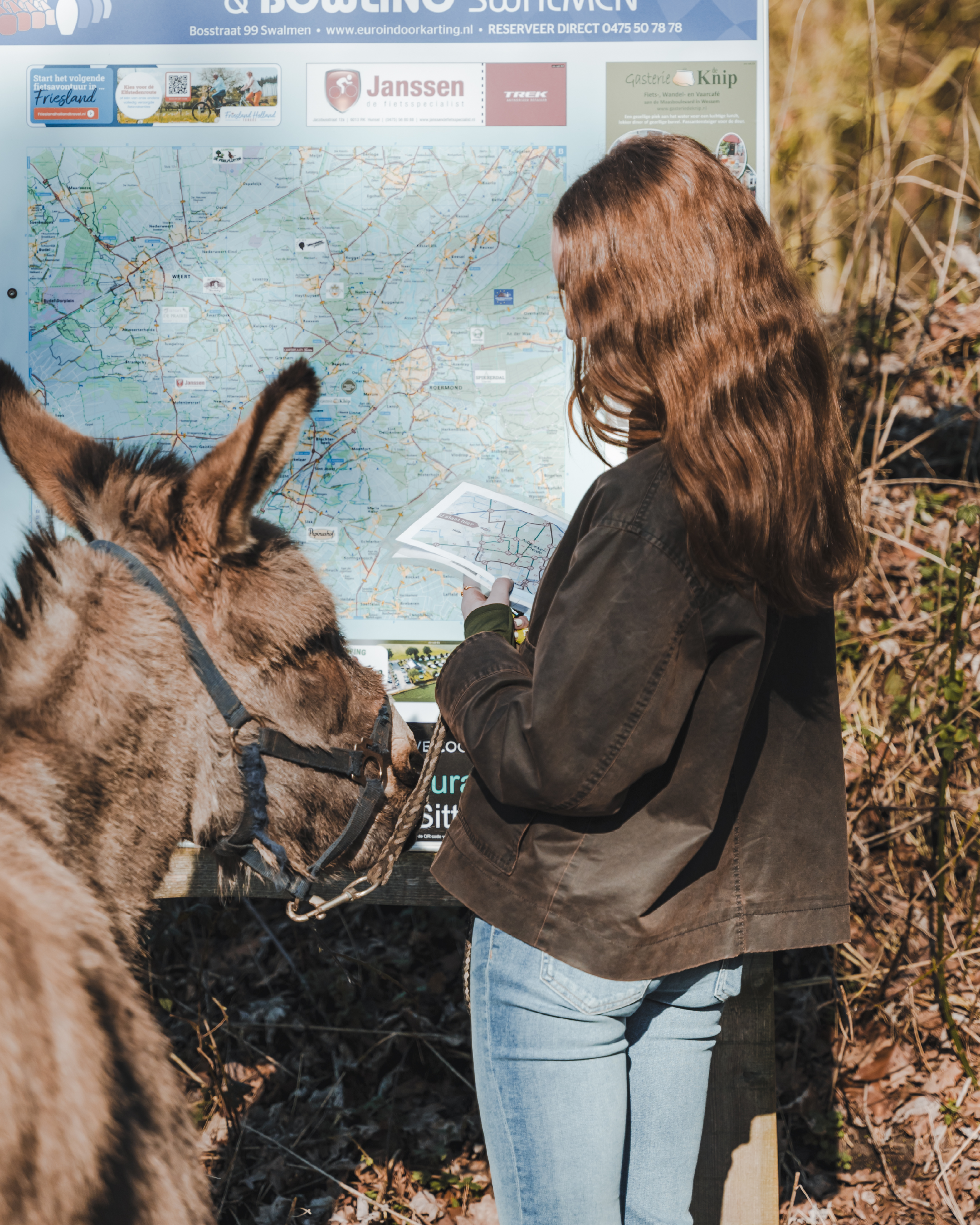 ezel en meisje kijken naar bord met wandelroute