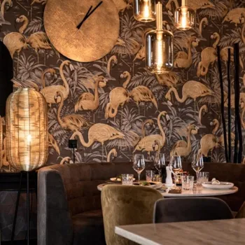 Sfeervol gedekte tafel bij Riverside Lounge in Maasbracht, met warme verlichting en opvallend flamingobehang op de achtergrond.