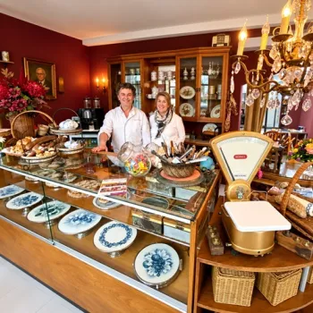 Bakker Ard Gerards en zijn vrouw May achter de toonbank van Beleefbakkerij Gerards-Steeghs, omringd door oude bakkersspullen.